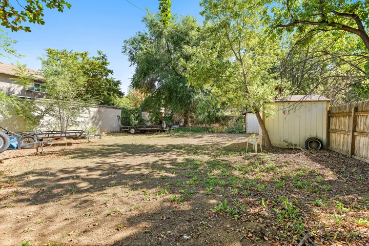 Expansive backyard with a wood privacy fence, mature trees, and a storage shed