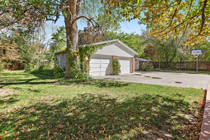 Detached two-car garage with overhead doors and established trees