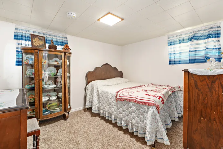 Basement bedroom, carpeted flooring, white walls, and a dropped ceiling with recessed lighting