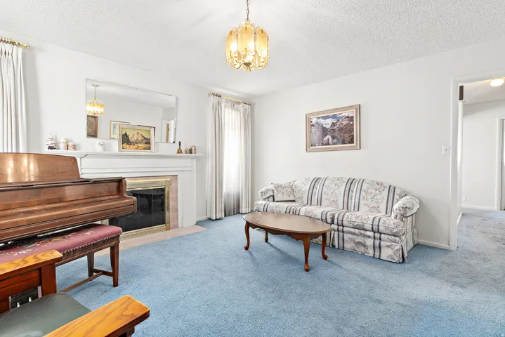 White walls, a built-in fireplace, a mantel, a gold chandelier, and a large mirror