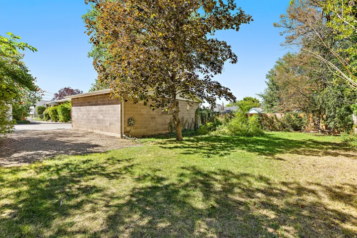 Expansive outdoor space featuring a detached garage and mature trees