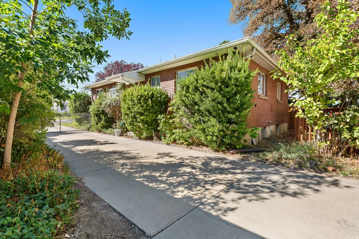Brick exterior with white soffits and fascia, mature landscaping, and an extended concrete driveway