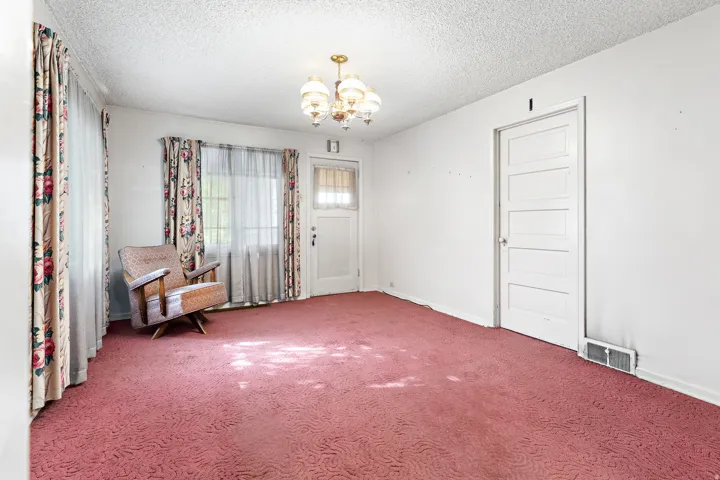 Textured ceiling, wall-to-wall carpeting, and a multi-panel interior door