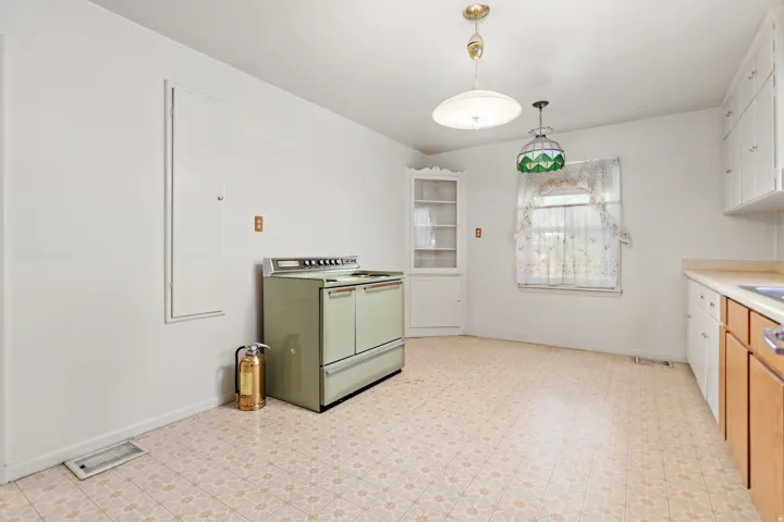 Kitchen featuring a built-in corner cabinet, overhead lighting fixtures, and a window