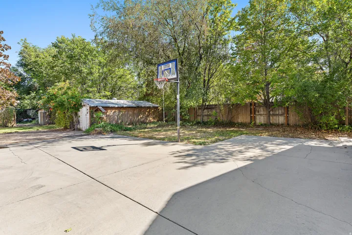 Concrete hardscaping, wood privacy fencing, and mature trees