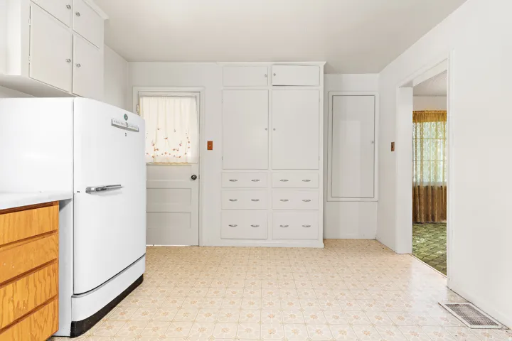 White cabinetry with chrome hardware, extensive built-in storage, and tile flooring