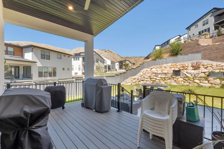 Expansive covered deck with composite wood-finish decking, black metal railings, and integrated ceiling lighting
