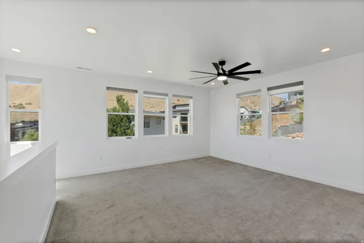 Spacious room featuring multiple windows, recessed lighting, a ceiling fan, and light-toned carpeting