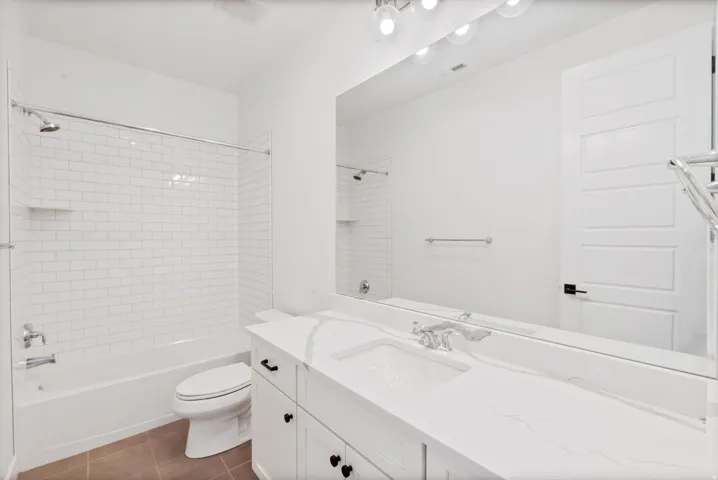 White subway tile shower surround with a built-in shelf, white vanity with a rectangular undermount sink, and a large wall-mounted mirror