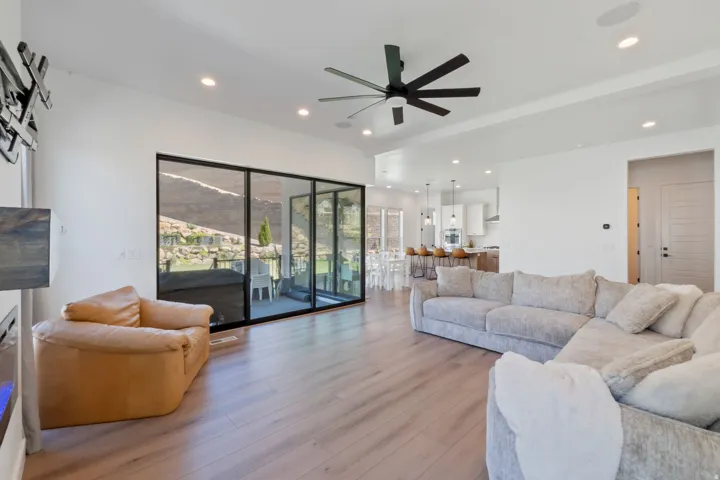 Expansive open-concept living space with wood-finish flooring, recessed lighting, and a modern ceiling fan