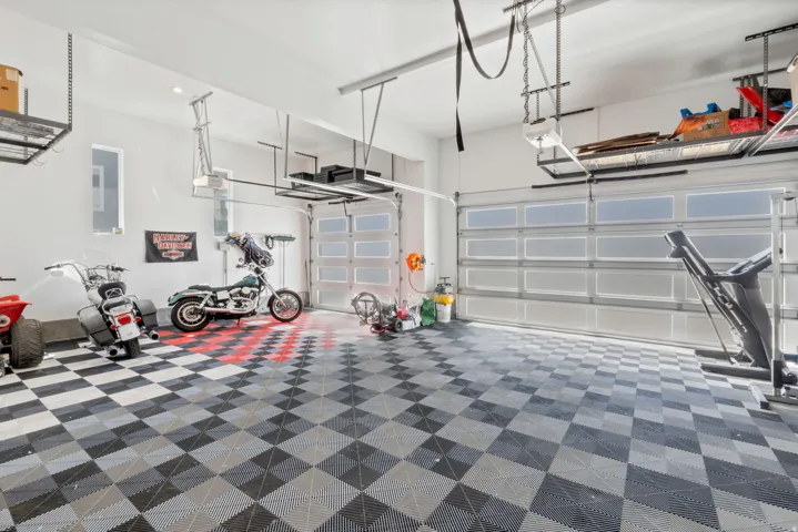 Chequered flooring, dual overhead garage doors with frosted panels, high ceilings with recessed lighting, and integrated overhead storage racks