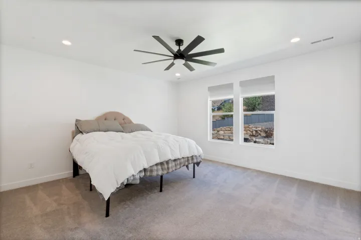Spacious room featuring neutral carpeting, a ceiling fan, recessed lighting, and two windows