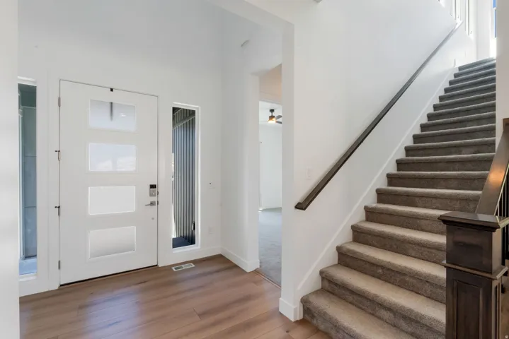 Bright foyer featuring a white 4-panel entry door with sidelights, warm wood-finish flooring