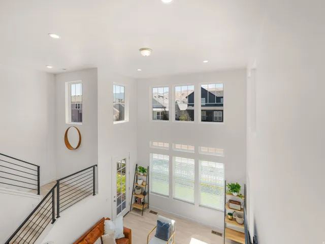 Two-story living space featuring high ceilings, multiple windows, recessed lighting, and a modern staircase with a black metal railing