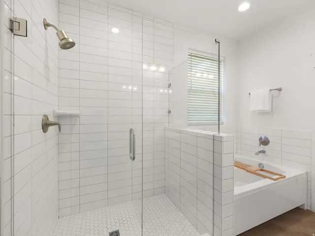 Walk-in shower with clear glass enclosure and hexagon tile floor