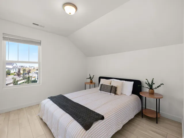 Sloped ceiling room featuring a double-hung window, flush mount lighting, and light wood-finish flooring