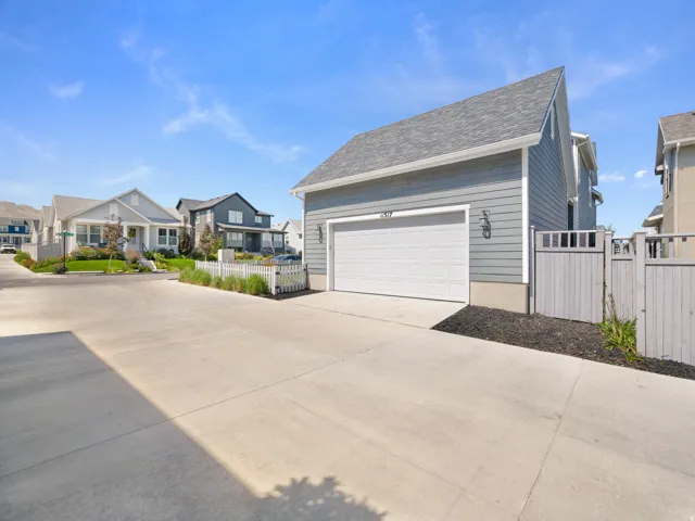 Attached garage with a white panel door, exterior wall sconces, and gray siding
