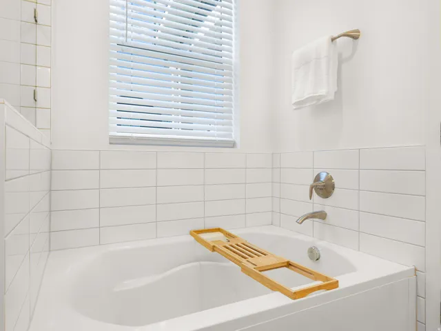 Built-in soaking tub with brushed nickel fixtures and white subway tile surround