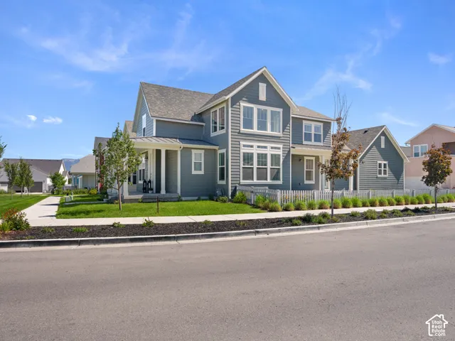 Two-story residence featuring horizontal siding, multiple gables, a covered front porch with columns, and a picket fence