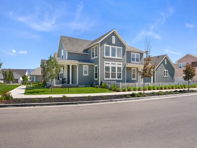 Two-story residence featuring horizontal siding, multiple gables, a covered front porch with columns, and a picket fence