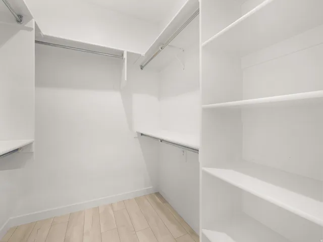 Integrated closet system featuring multiple hanging rods, extensive shelving, and wood-finish flooring