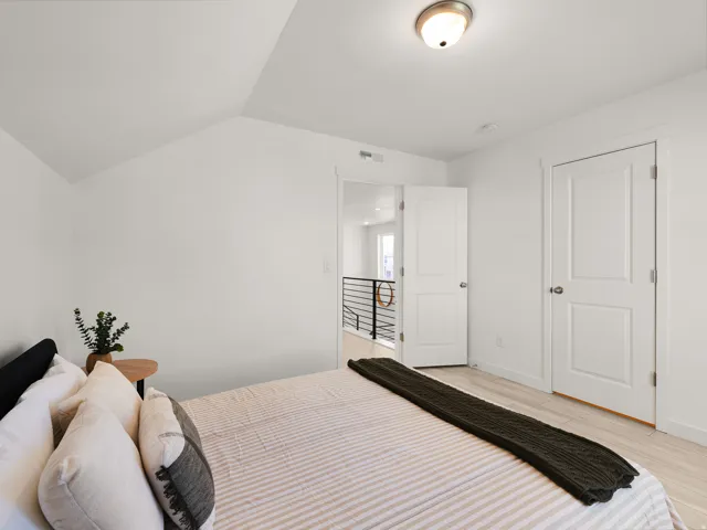 Vaulted ceiling, ceiling-mounted light fixture, white interior doors, wood-finish flooring, white walls