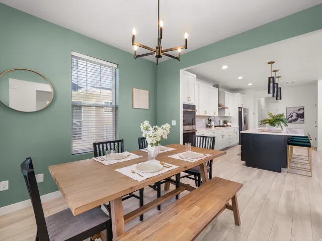 Dining area with light wood-finish flooring, featuring a modern chandelier and a window with blinds