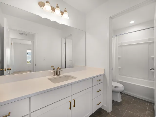 Long vanity featuring an undermount sink, brushed nickel faucet, and white cabinetry with gold-tone hardware