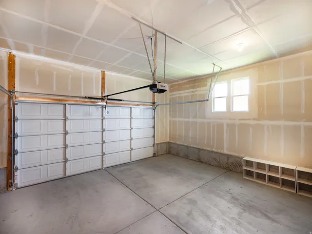 Spacious garage featuring a paneled overhead door and concrete flooring