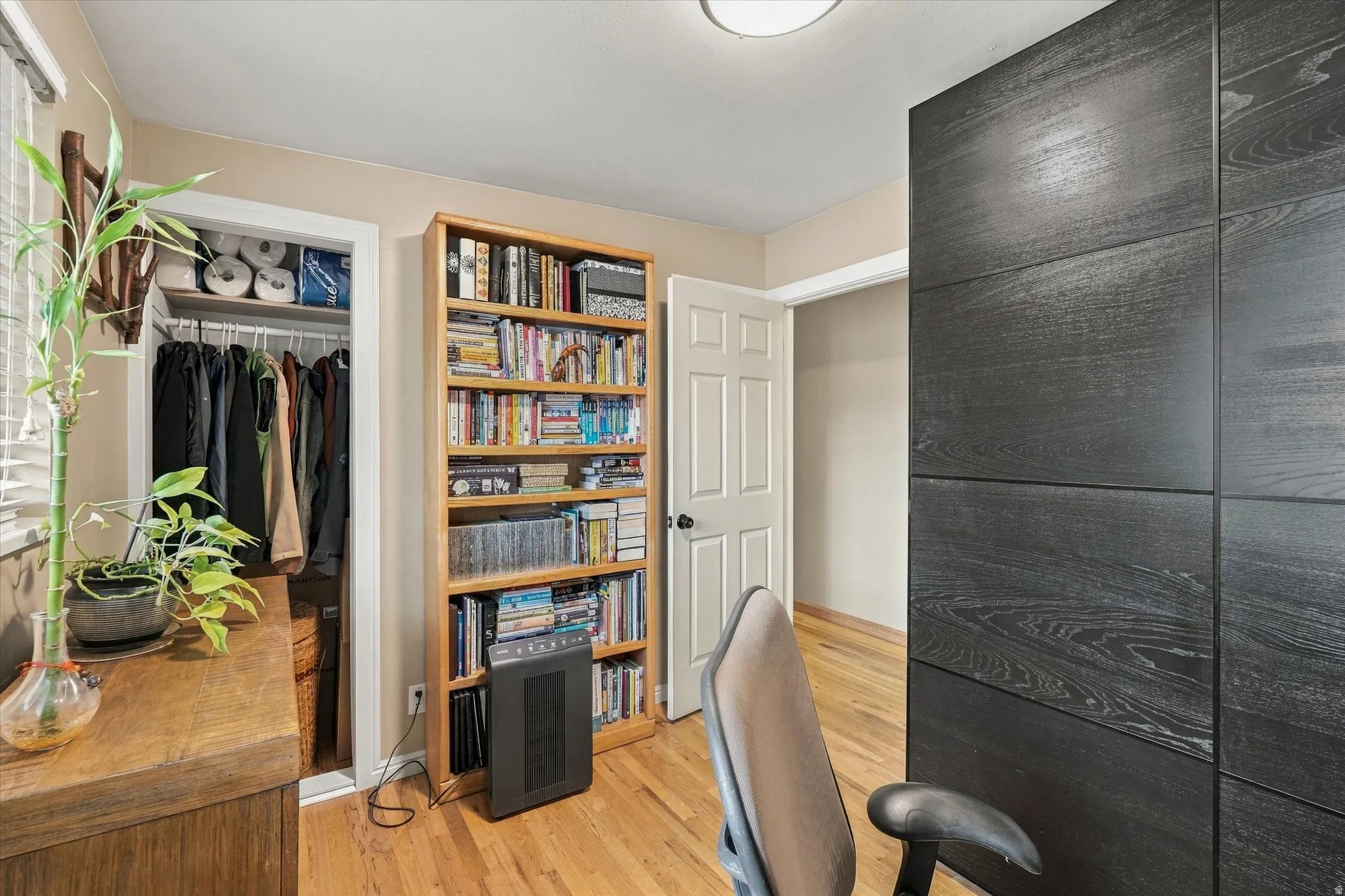 Hardwood flooring throughout, featuring a built-in shelving unit, a closet with shelving and hanging storage, and a paneled accent wall