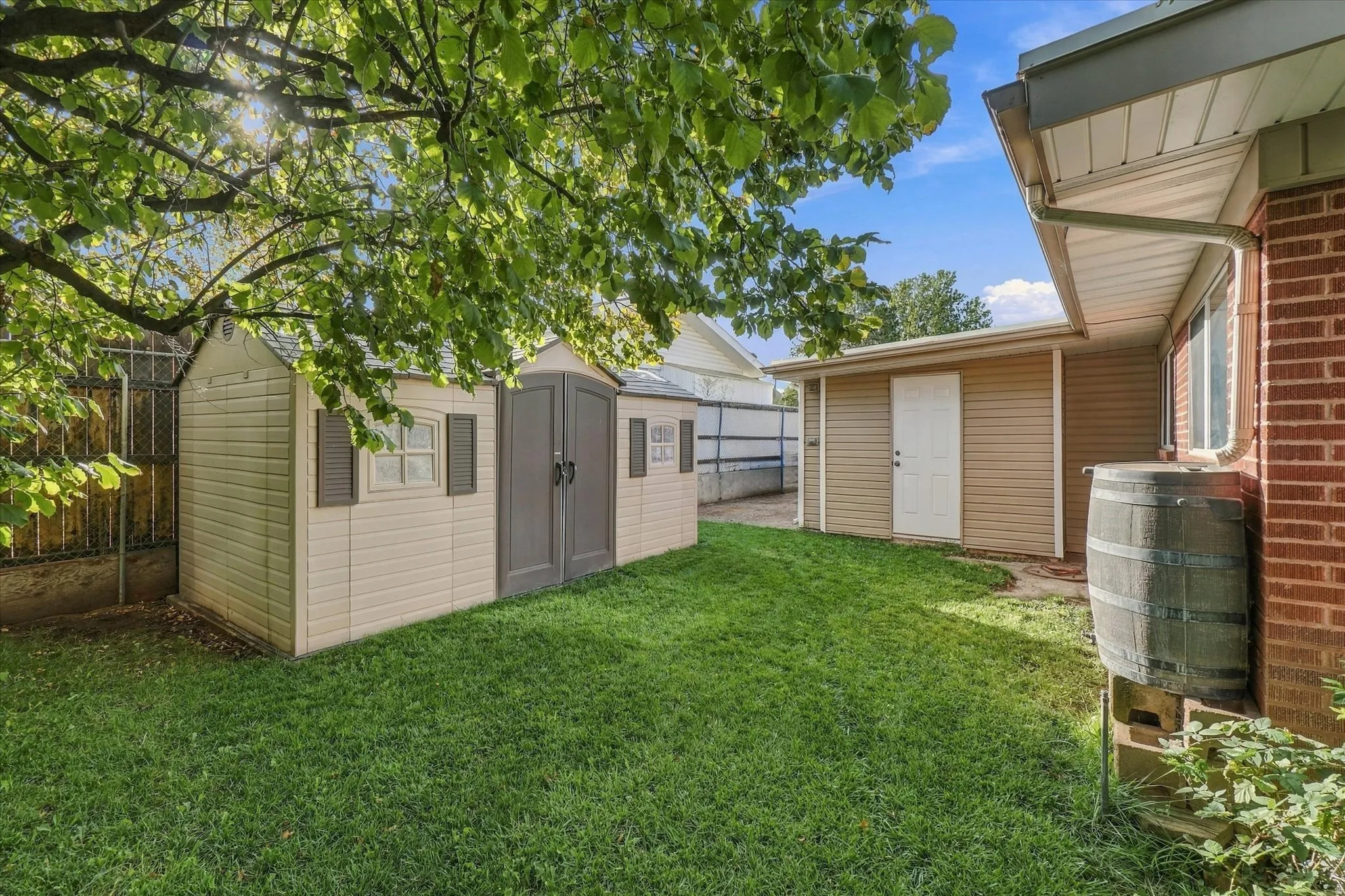 Grassed yard featuring a storage shed, secondary detached structure, and brick exterior