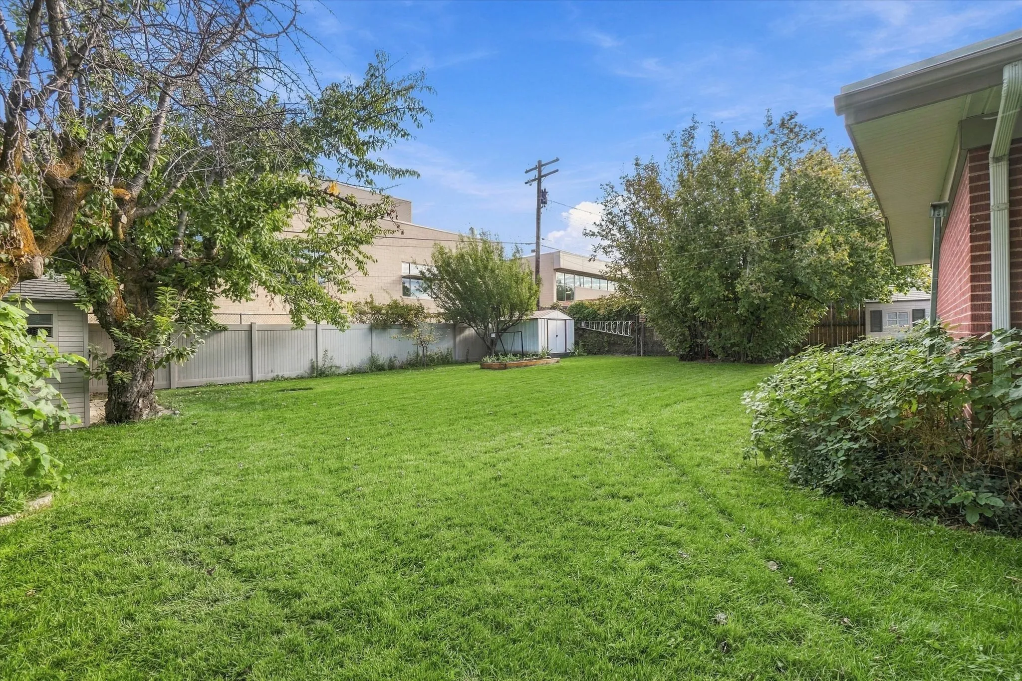 Expansive lawn area with mature trees and perimeter fencing
