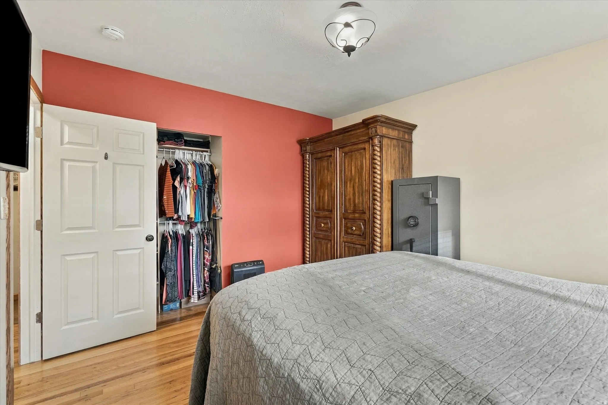 Hardwood-style flooring, a built-in closet with shelving and hanging rods, and a decorative ceiling light fixture