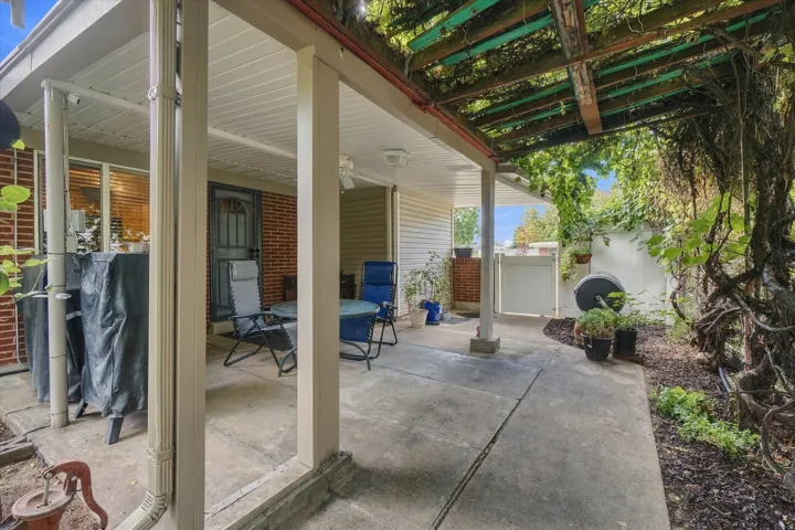 Covered patio area with concrete flooring, supported by multiple posts, and a wood lattice pergola