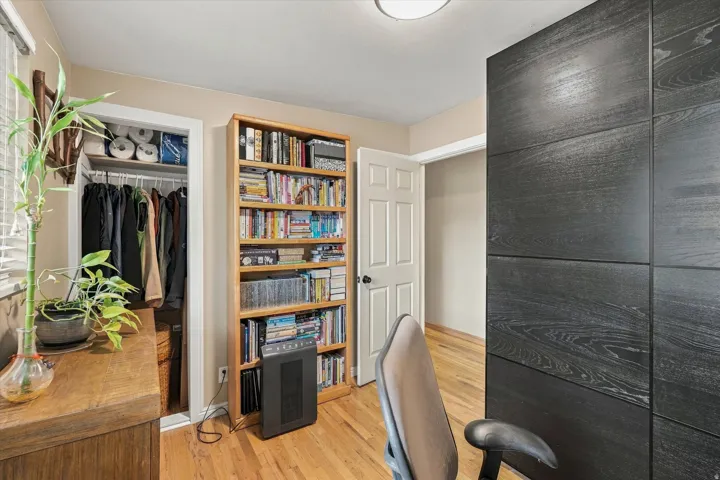 Hardwood flooring throughout, featuring a built-in shelving unit, a closet with shelving and hanging storage, and a paneled accent wall