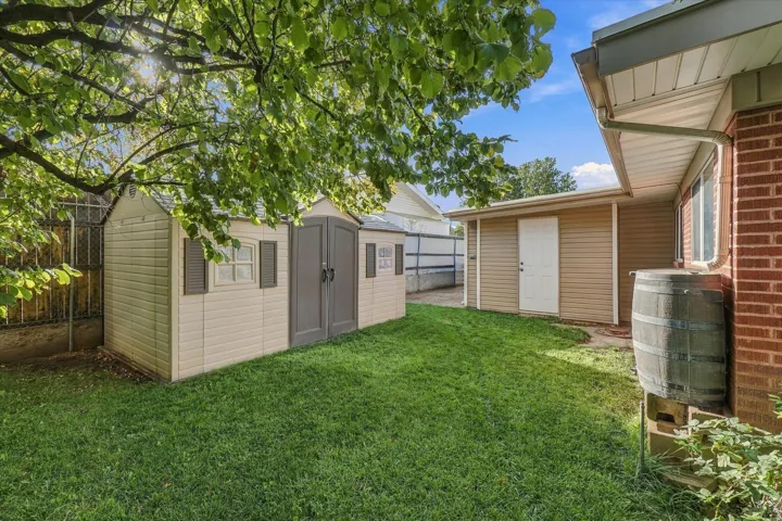 Grassed yard featuring a storage shed, secondary detached structure, and brick exterior