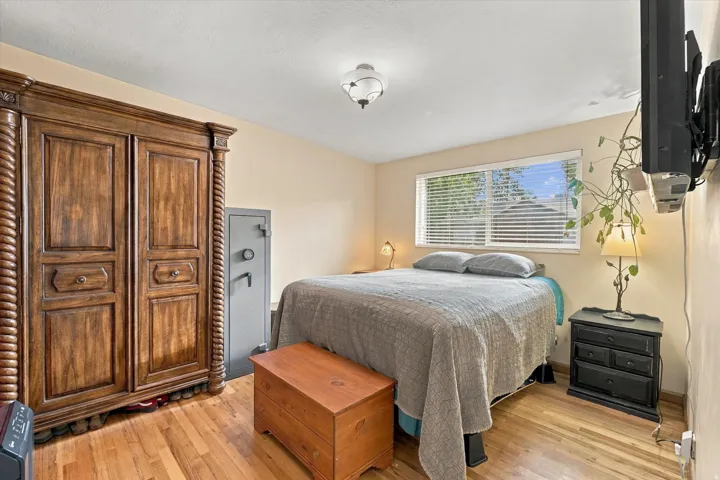 Wood-finish flooring with a neutral wall color, featuring a window with blinds