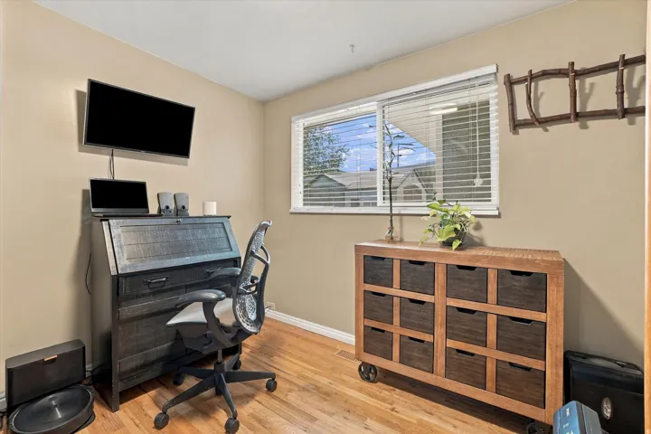 Hardwood flooring, neutral wall tones, horizontal window blinds, and built-in wall shelving