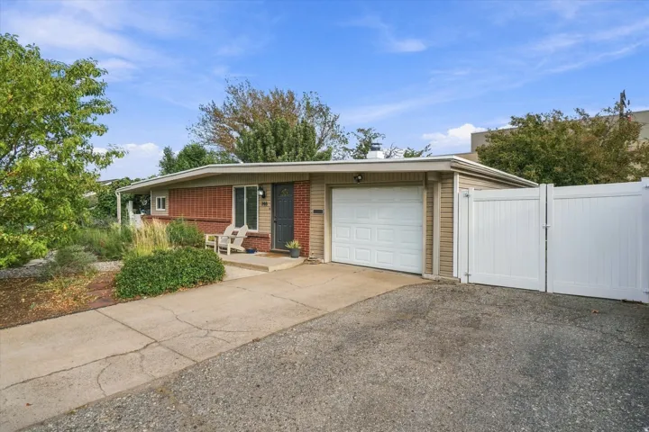 Brick and siding exterior with an attached garage, concrete driveway, and a white privacy gate
