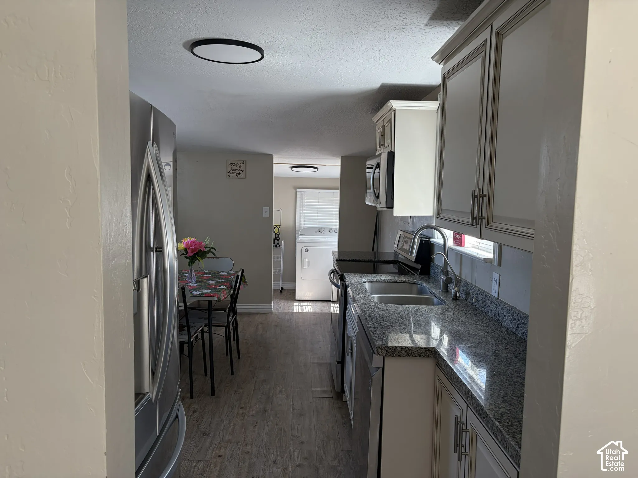 Modern kitchen featuring stainless steel appliances, dual basin sink, and granite countertops