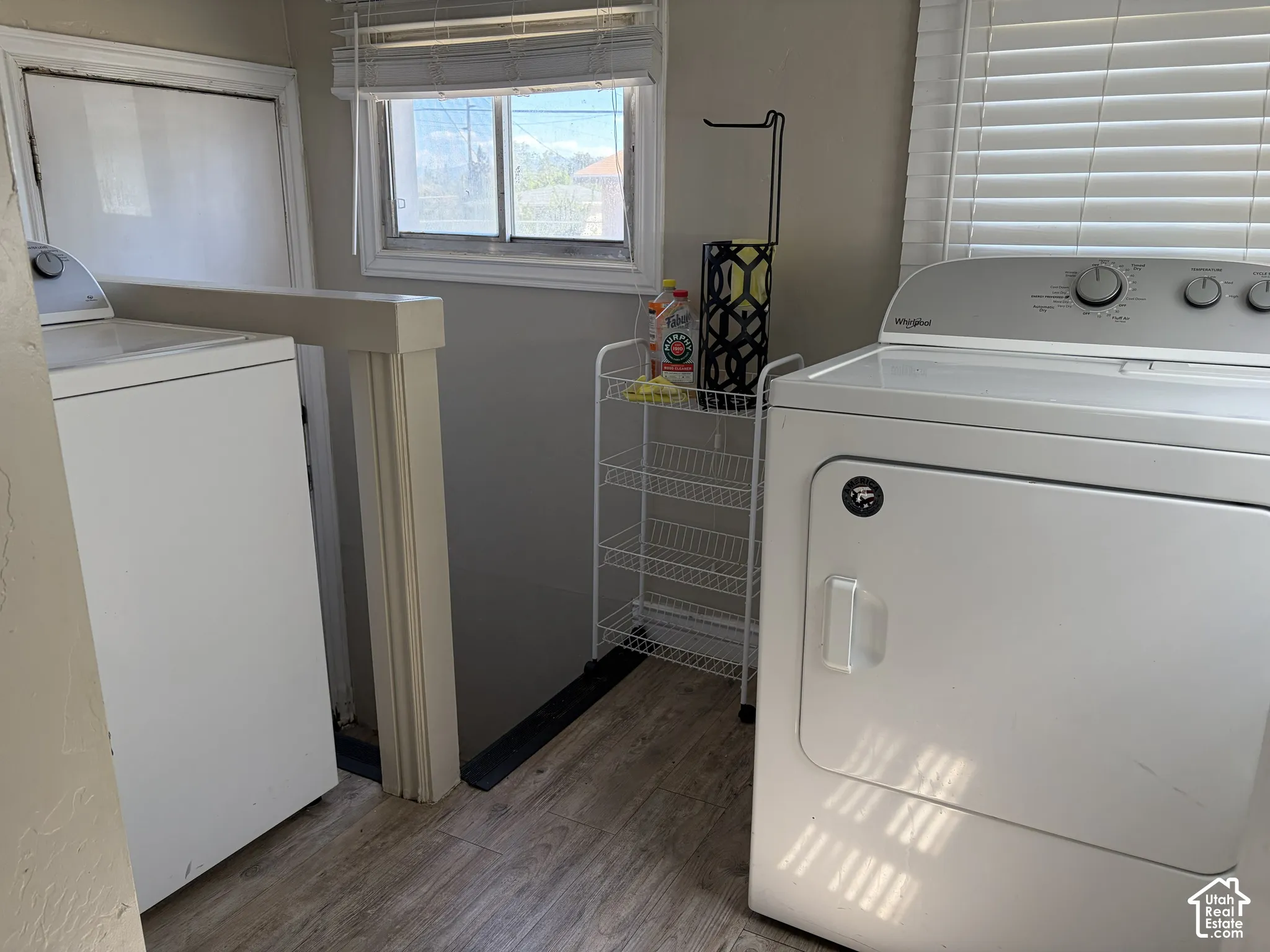 Laundry area with wood-finish flooring and a window with blinds