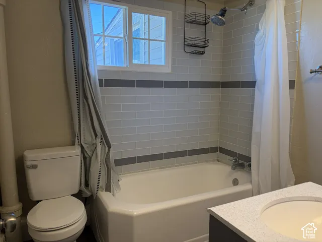 White porcelain bathtub with subway tile surround, integrated shower fixture, and a single-pane window