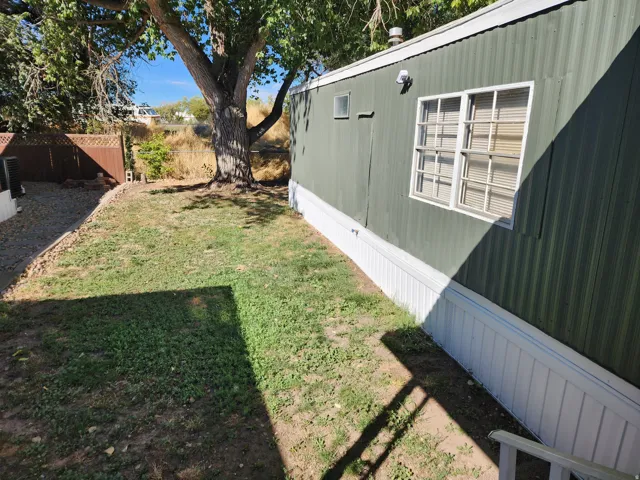 Side yard featuring a mature tree, gravel bed, and a brown privacy fence