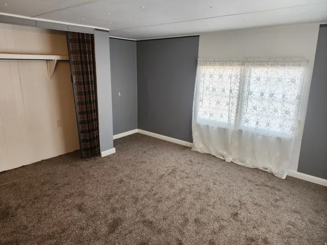 Carpeted room featuring a white paneled wall and a dark accent wall
