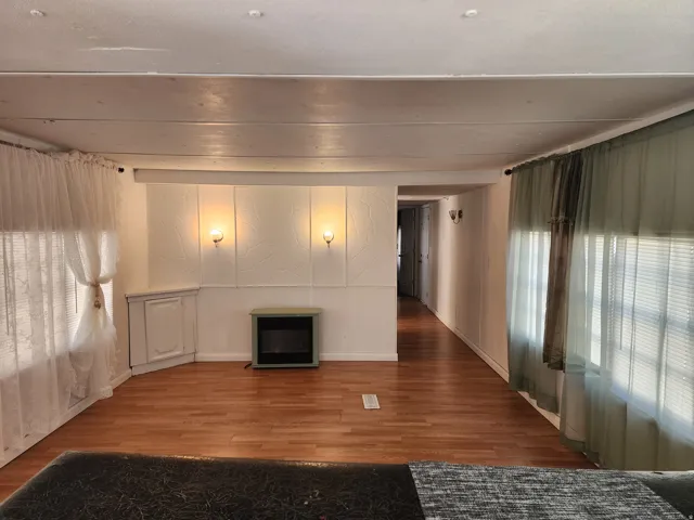 Wood-finish flooring throughout, featuring a built-in fireplace, wall sconces, and a corner cabinet
