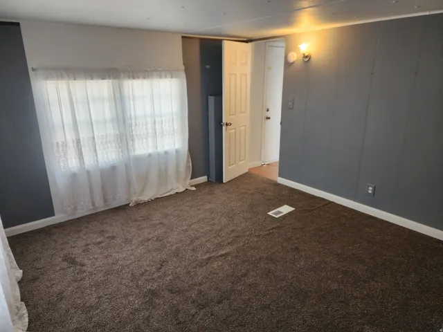 Dark gray paneled accent wall, neutral tone carpeting, white trim, and a white interior door