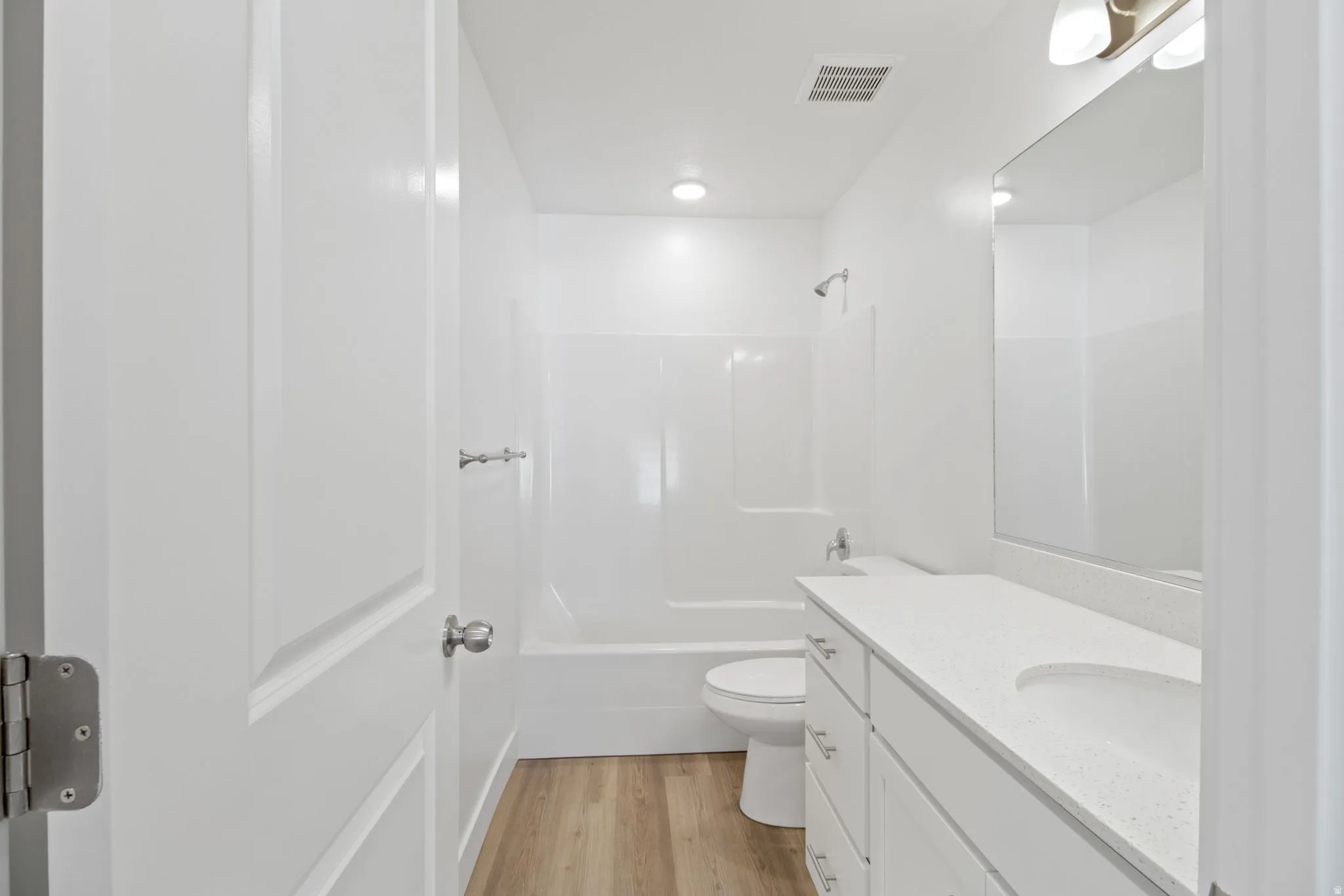 White vanity with an integrated sink, polished chrome fixtures, and a large wall-mounted mirror
