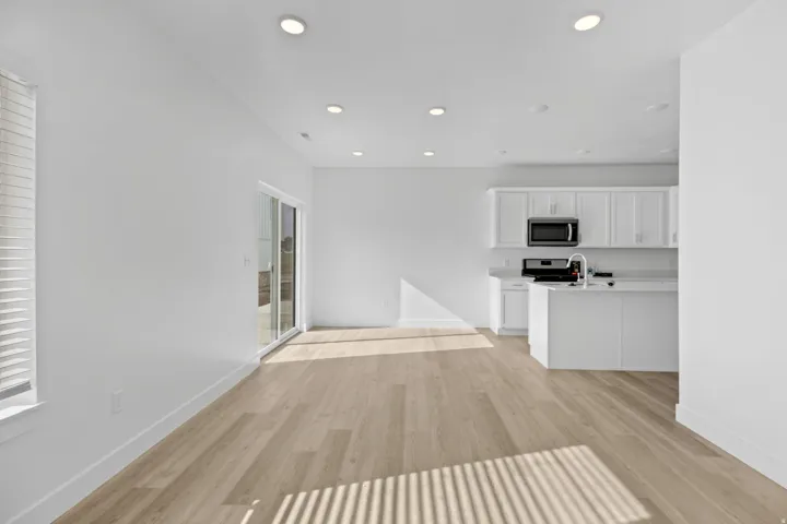 Open-concept living space featuring wood-finish flooring, recessed lighting, and a sliding glass door