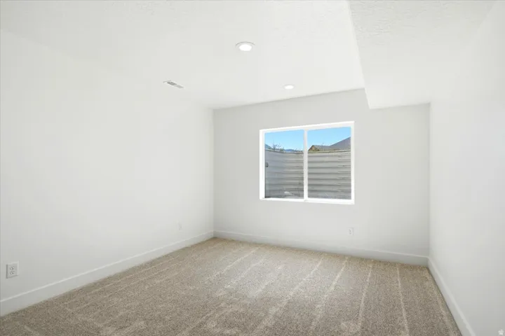Neutral carpeting, white wall paint, recessed lighting, white window trim, and a white ceiling