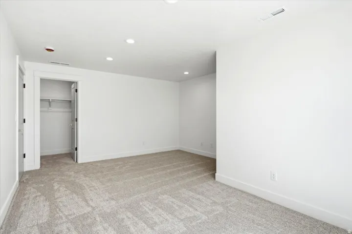 Recessed lighting, light-toned carpeting, and a built-in closet with shelving